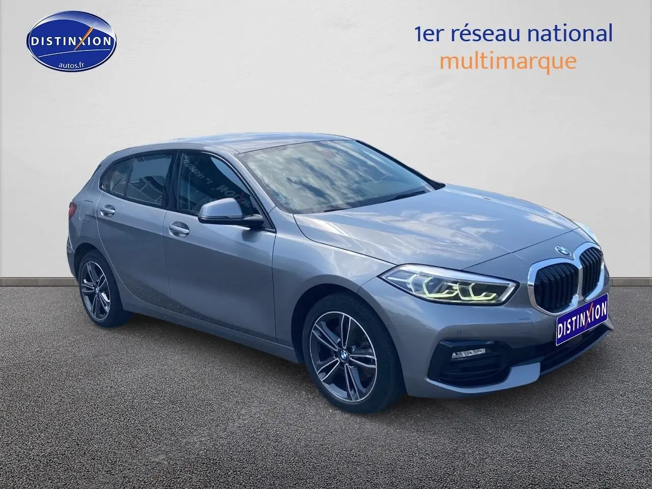 BMW Série 1 gris foncé vue 3/4 avant droit avec phares LED allumés et jantes alliage 17 pouces style 549.