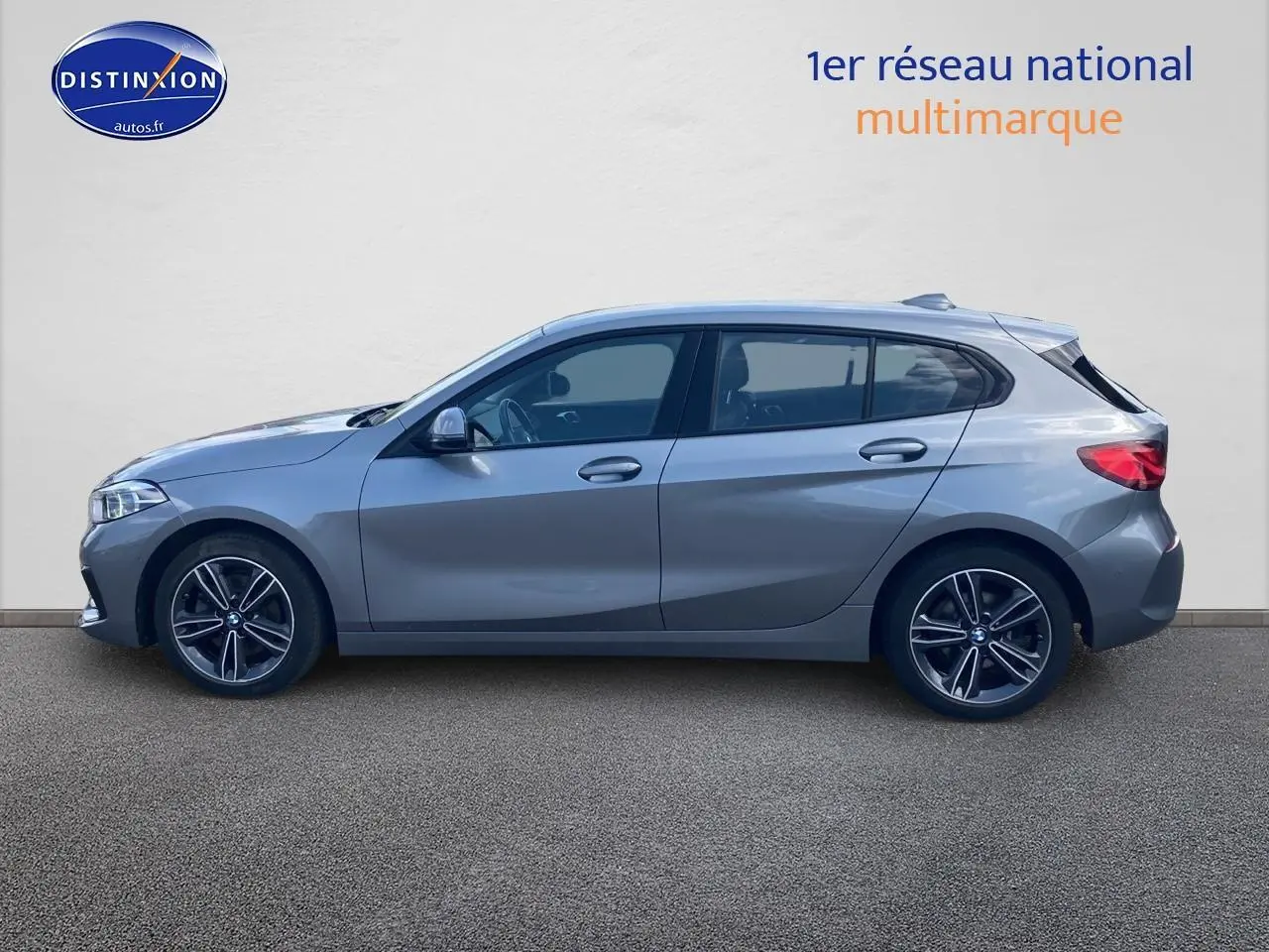 Profil droit d'une BMW Série 1 118i 2023 gris foncé avec jantes alliage 17 pouces et lignes sportives marquées.