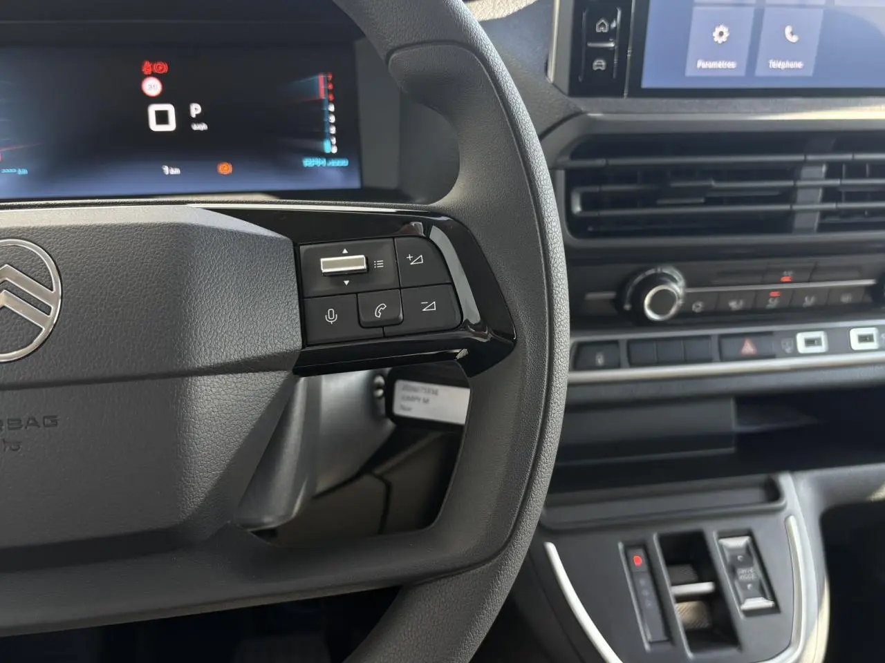 Vue rapprochée du volant et du tableau de bord noir du Citroën Jumpy 2026, avec commandes au volant et écran tactile visible.