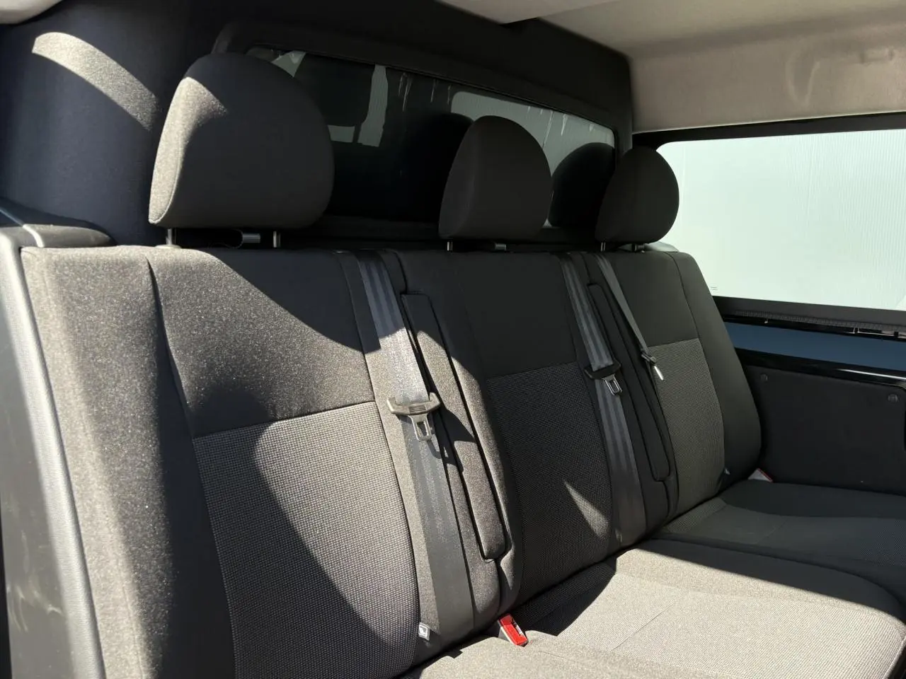 Vue intérieure de la banquette arrière grise du Citroën Jumpy noir Perla, avec ceintures et vitres latérales teintées.