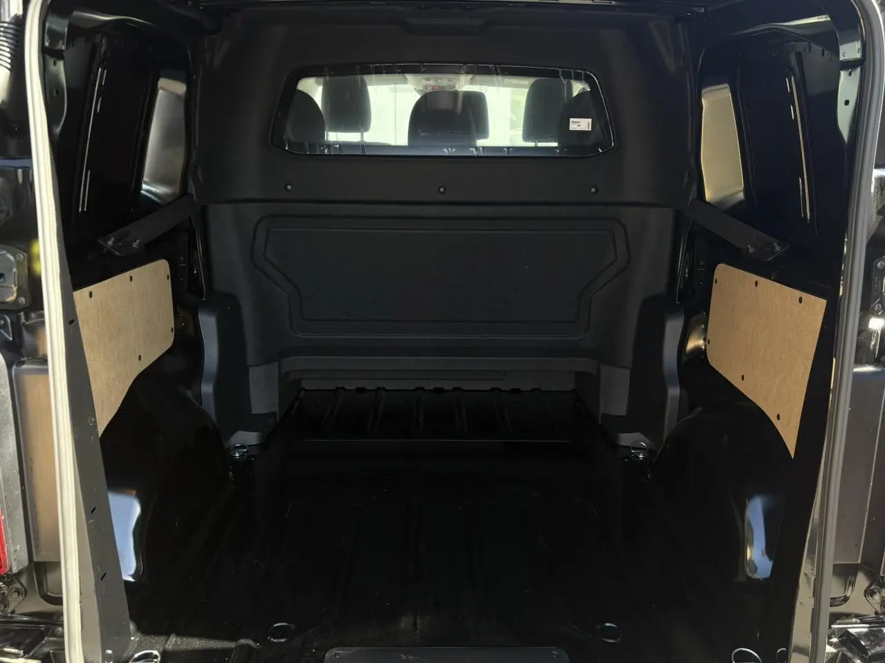 Vue intérieure arrière du Citroën Jumpy noir Perla, montrant l'espace de chargement vide et les panneaux latéraux en bois.