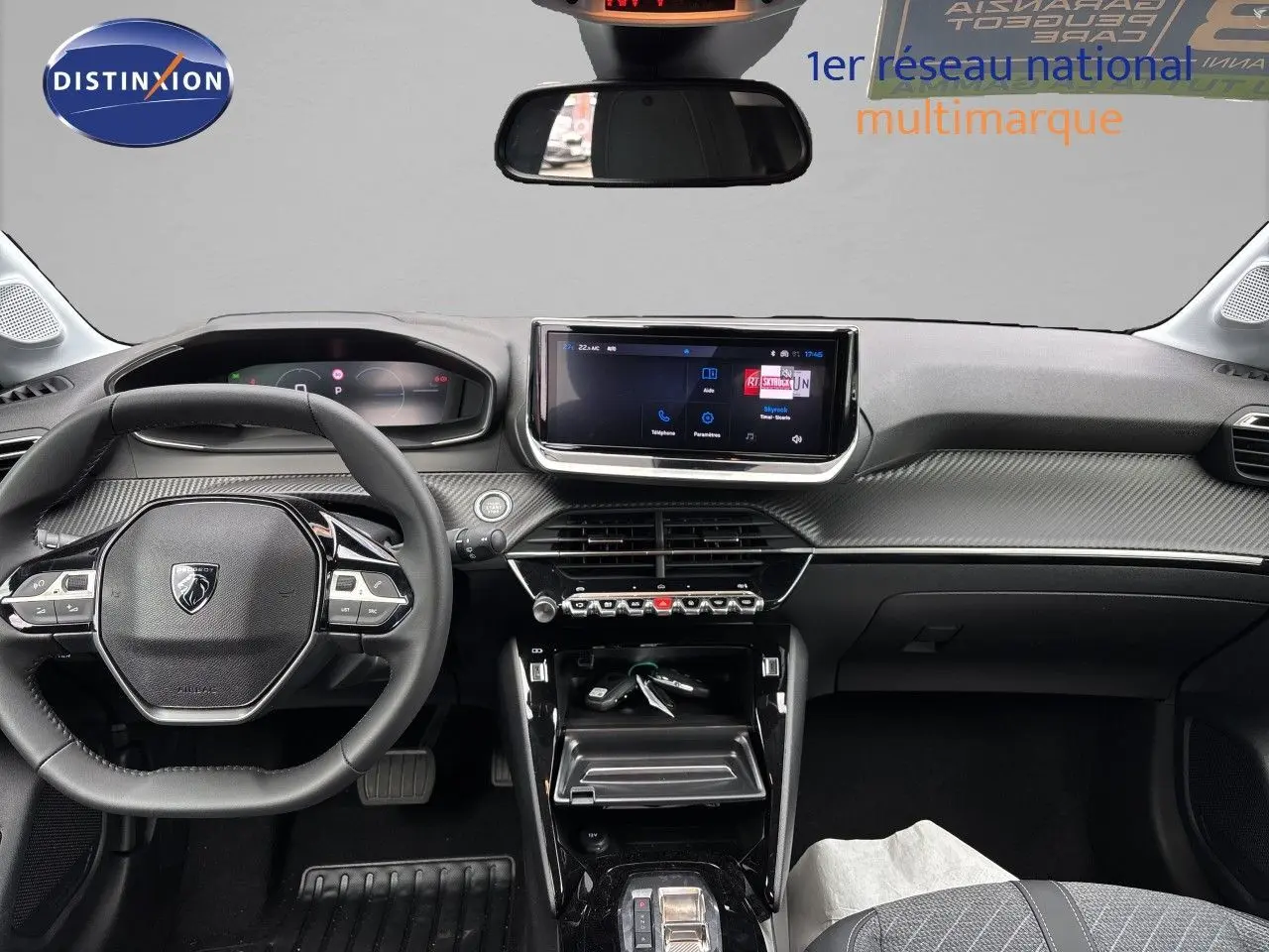 Vue intérieure avant de la Peugeot 208 électrique gris Artense, tableau de bord avec écran tactile et volant multifonction.