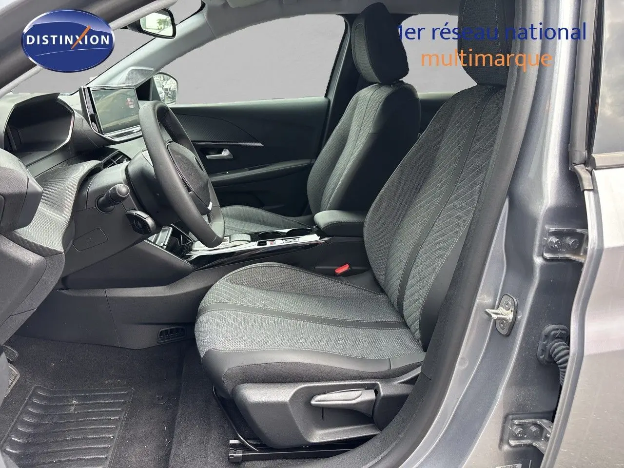 Intérieur côté conducteur de la Peugeot 208 électrique gris Artense, avec sièges tissu gris et tableau de bord moderne.