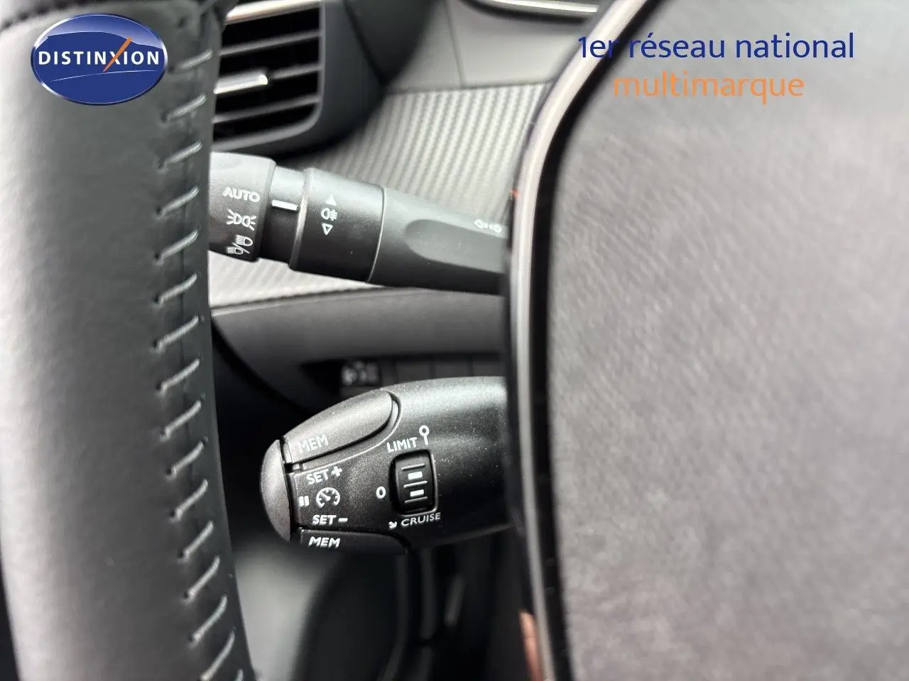 Gros plan sur la commande de régulateur de vitesse à gauche du volant d’une Peugeot 208 électrique gris Artense métal.