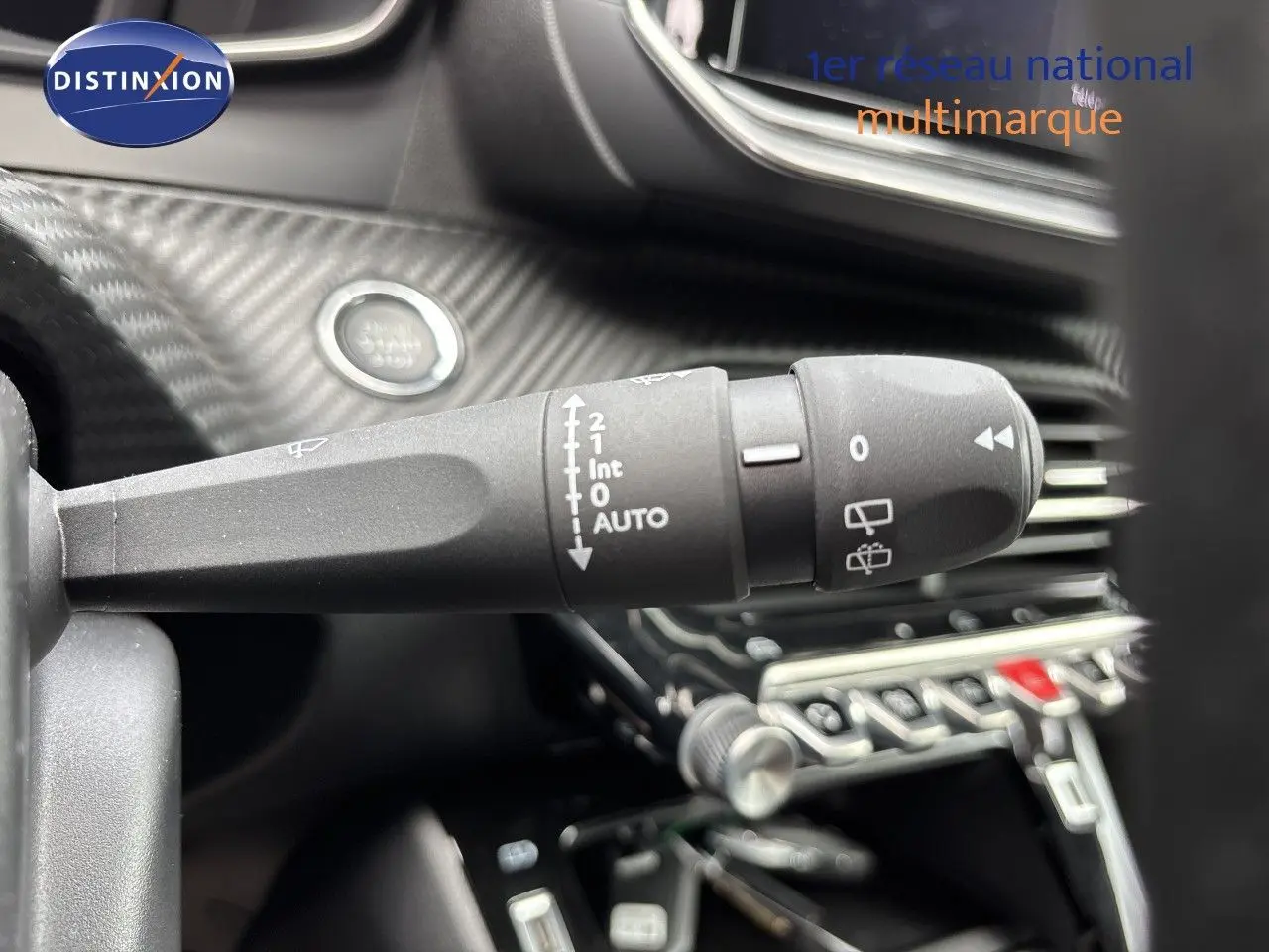Gros plan sur la commande d’essuie-glace à gauche du volant dans l’habitacle noir d’une Peugeot 208 électrique gris Artense.