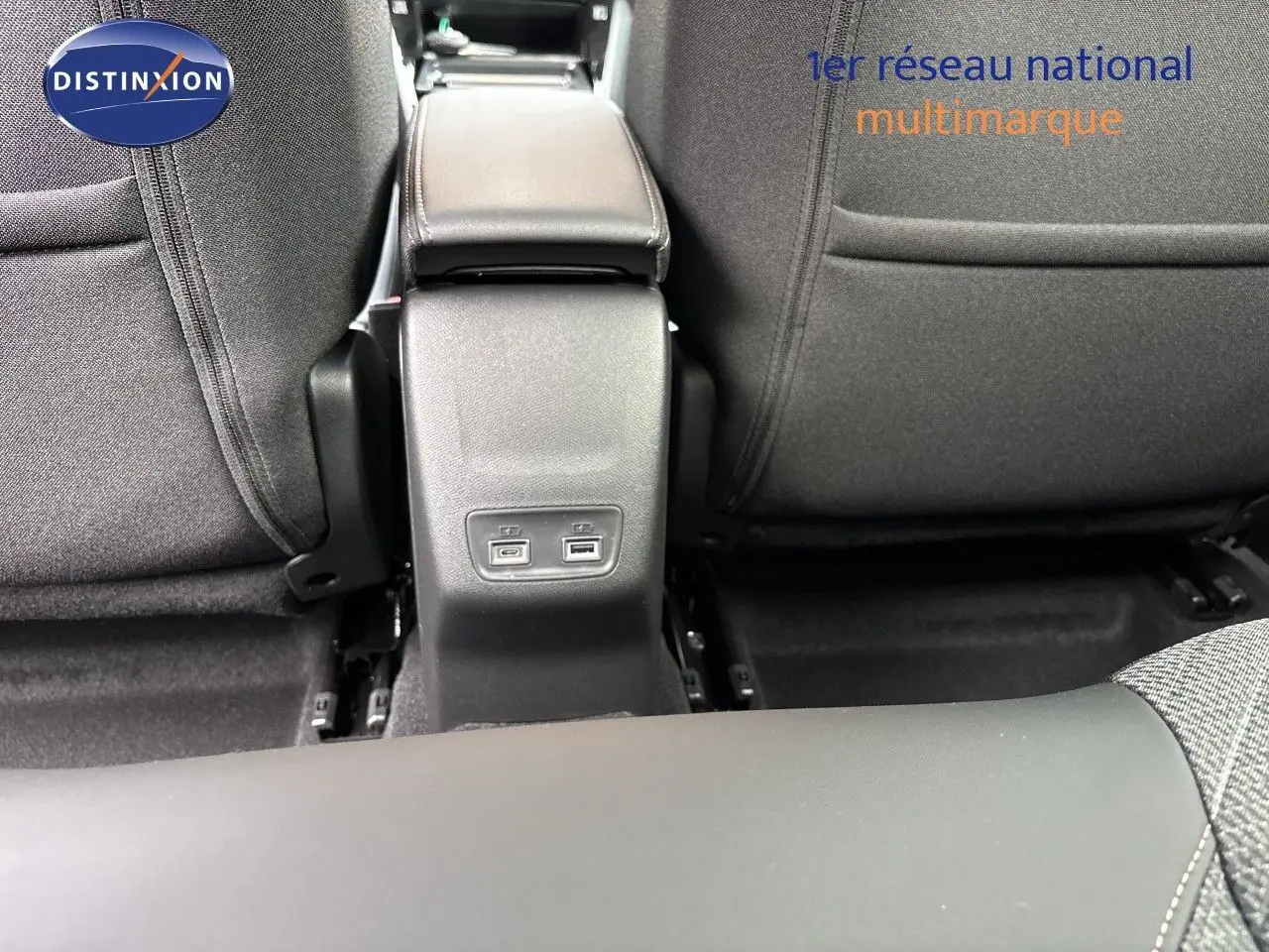 Vue rapprochée de la console centrale arrière avec ports USB, entre les sièges tissu gris d’une Peugeot 208 électrique 2026.