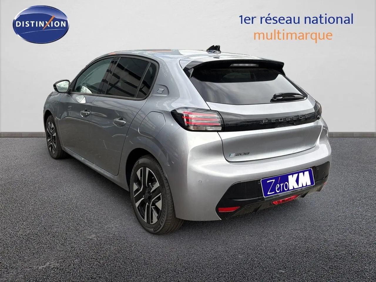 Vue 3/4 arrière droite d'une Peugeot 208 électrique gris Artense métal avec jantes noires et vitres teintées.