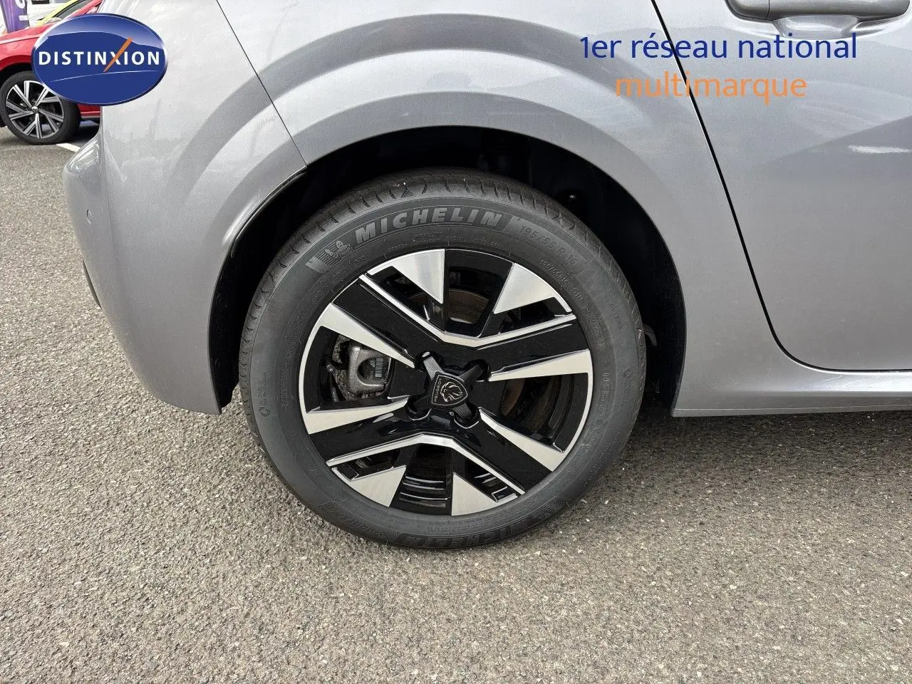 Gros plan sur la roue avant gauche de la Peugeot 208 électrique gris Artense métal avec jante alliage bicolore.