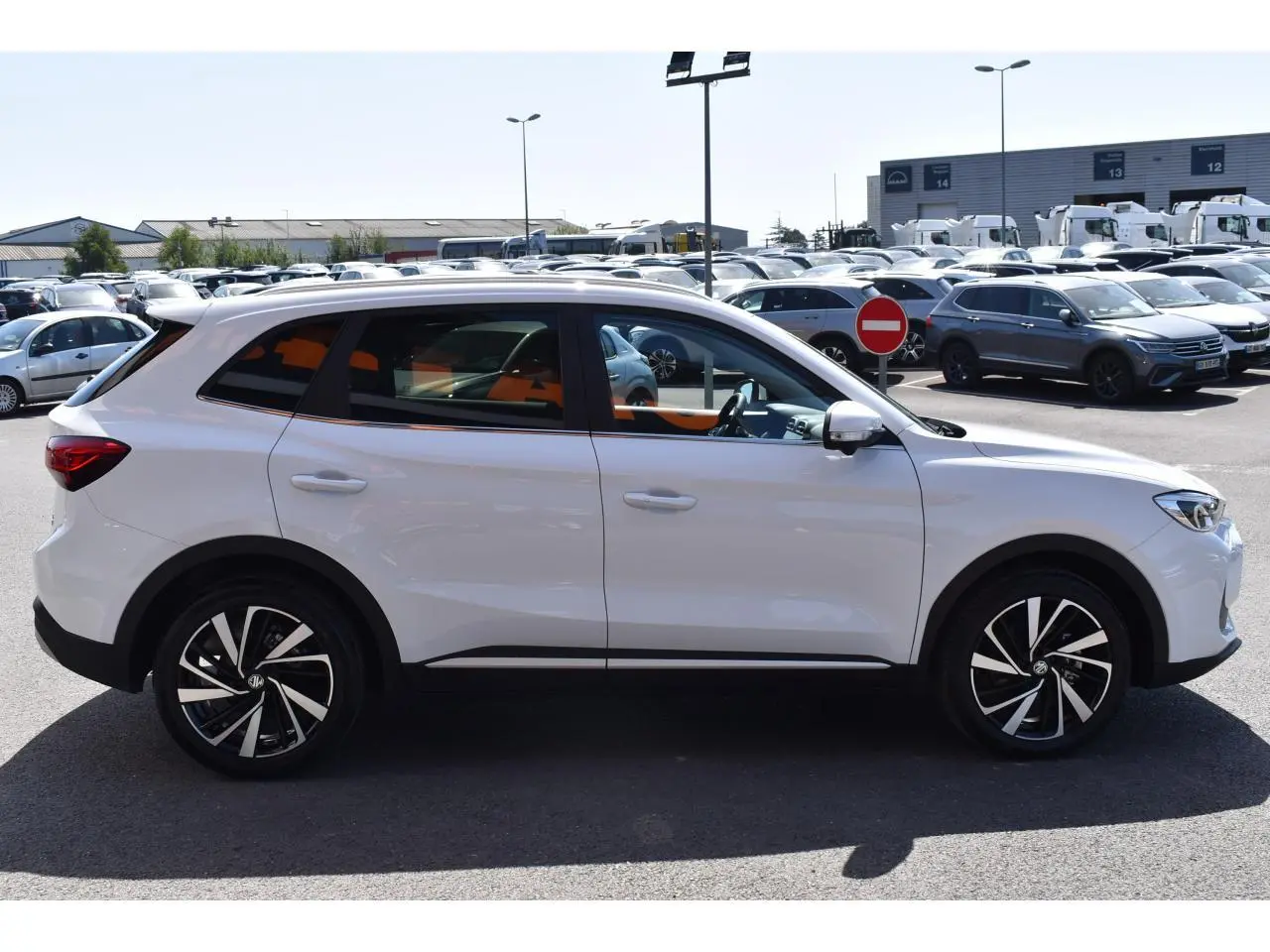 Vue de profil côté gauche d'un MG ZS blanc 2026 avec jantes alliage 18 pouces, garé en extérieur sur parking.