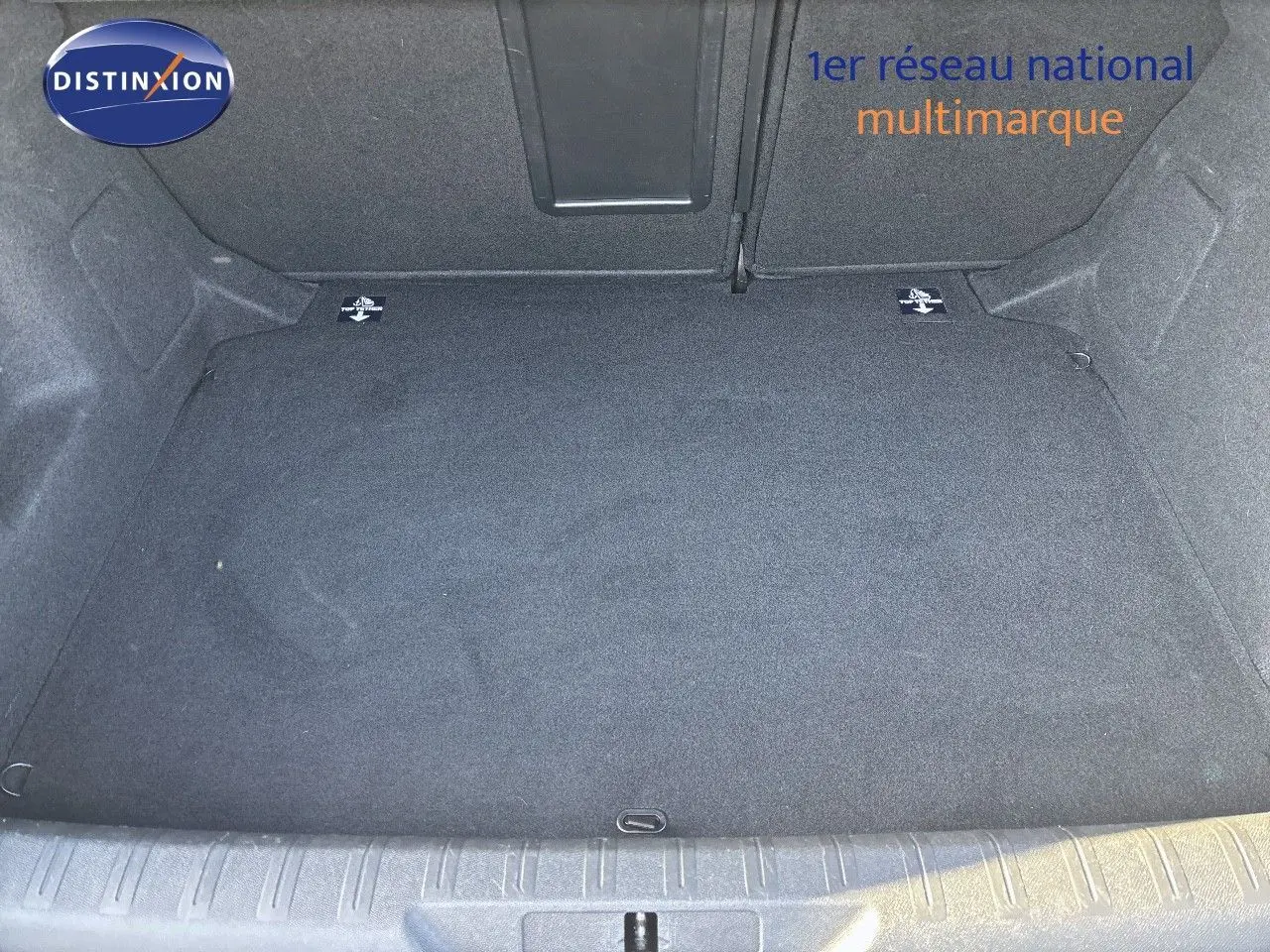 Coffre vide en tissu gris foncé d'une Peugeot 308 blanc nacré, vue de dessus depuis l'ouverture arrière.