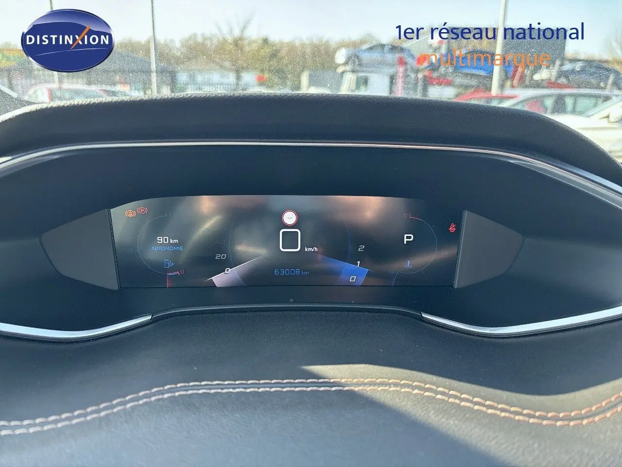 Tableau de bord numérique de Peugeot 308 blanc nacré 2021, affichant vitesse, autonomie et kilométrage.