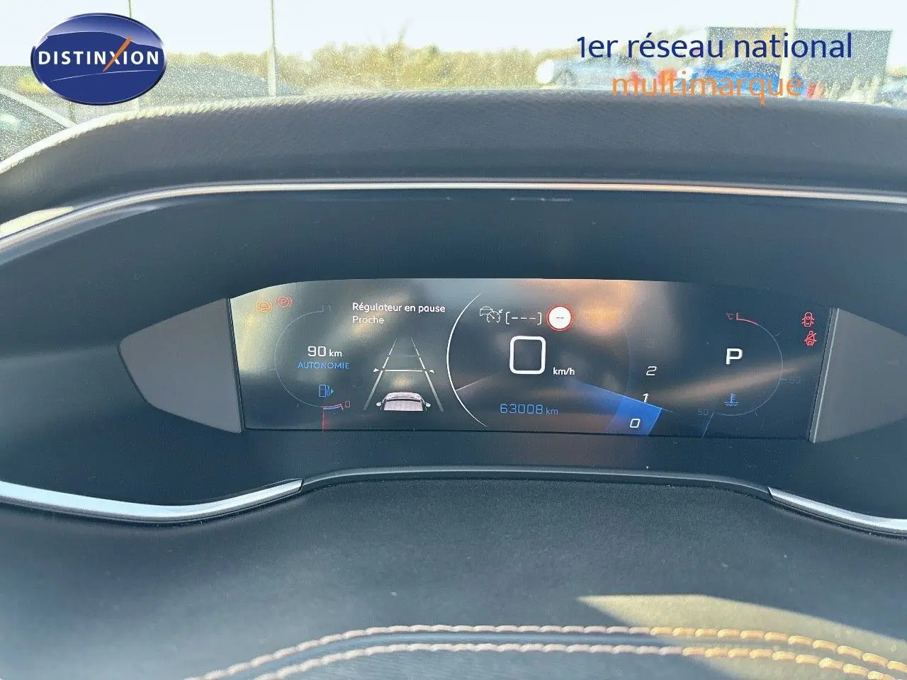 Affichage numérique du tableau de bord de la Peugeot 308 blanc nacré, montrant la vitesse à 0 km/h et l'autonomie restante.