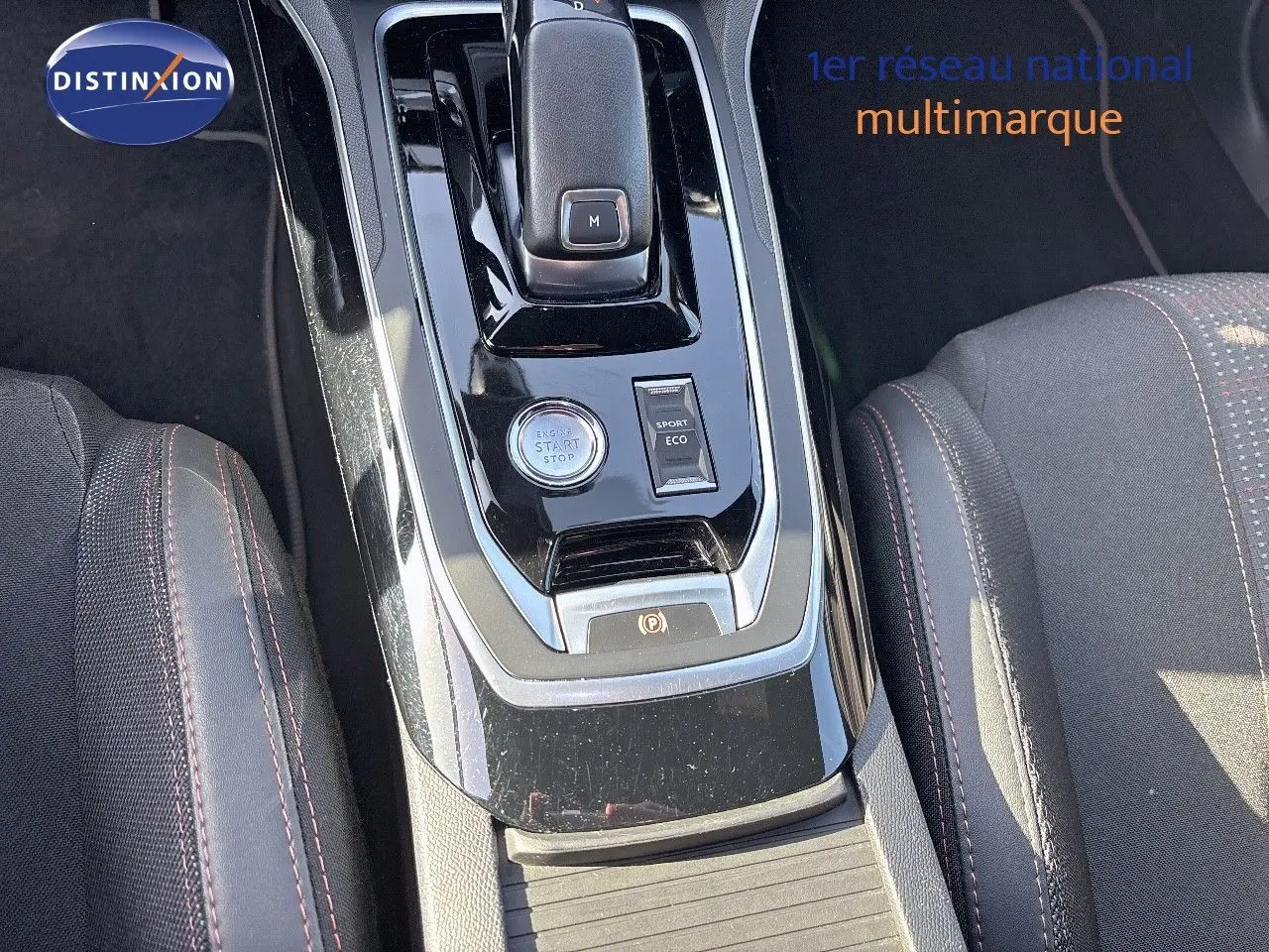 Gros plan sur la console centrale noire brillante de la Peugeot 308 blanche nacrée, avec levier de vitesse et boutons start/stop.