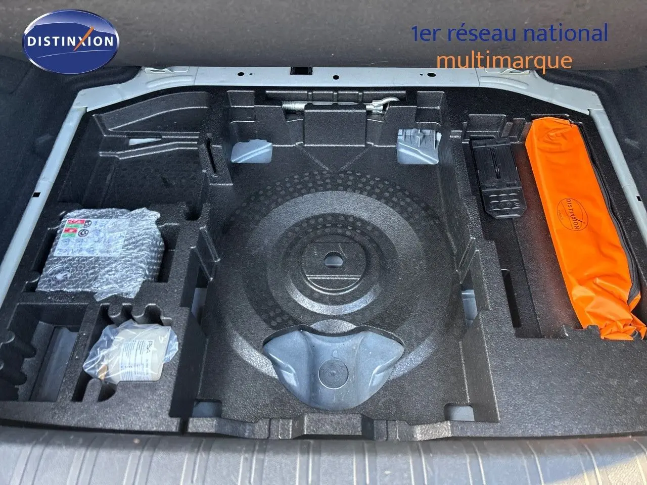 Compartiment de rangement sous le coffre de la Peugeot 308 blanc nacré, montrant les emplacements pour outils et accessoires.