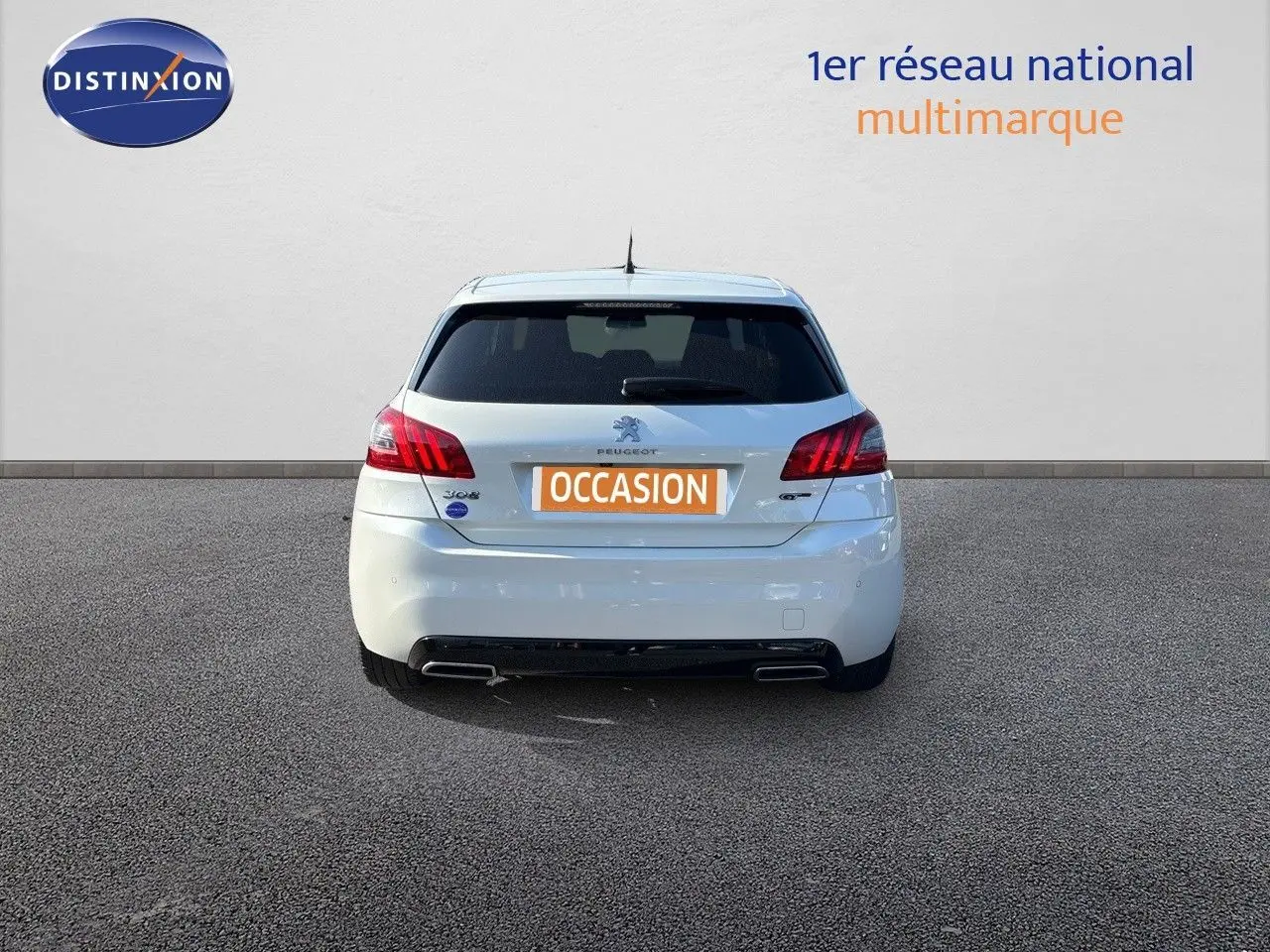 Vue arrière d'une Peugeot 308 GT blanche nacrée de 2021, avec feux rouges et double sortie d'échappement visible.