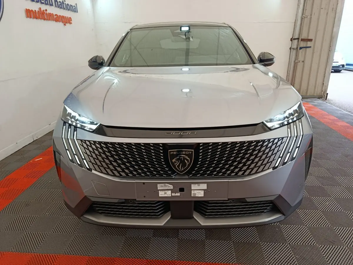Vue frontale du Peugeot 3008 gris clair 2025 avec calandre distinctive et phares LED en forme de griffes.