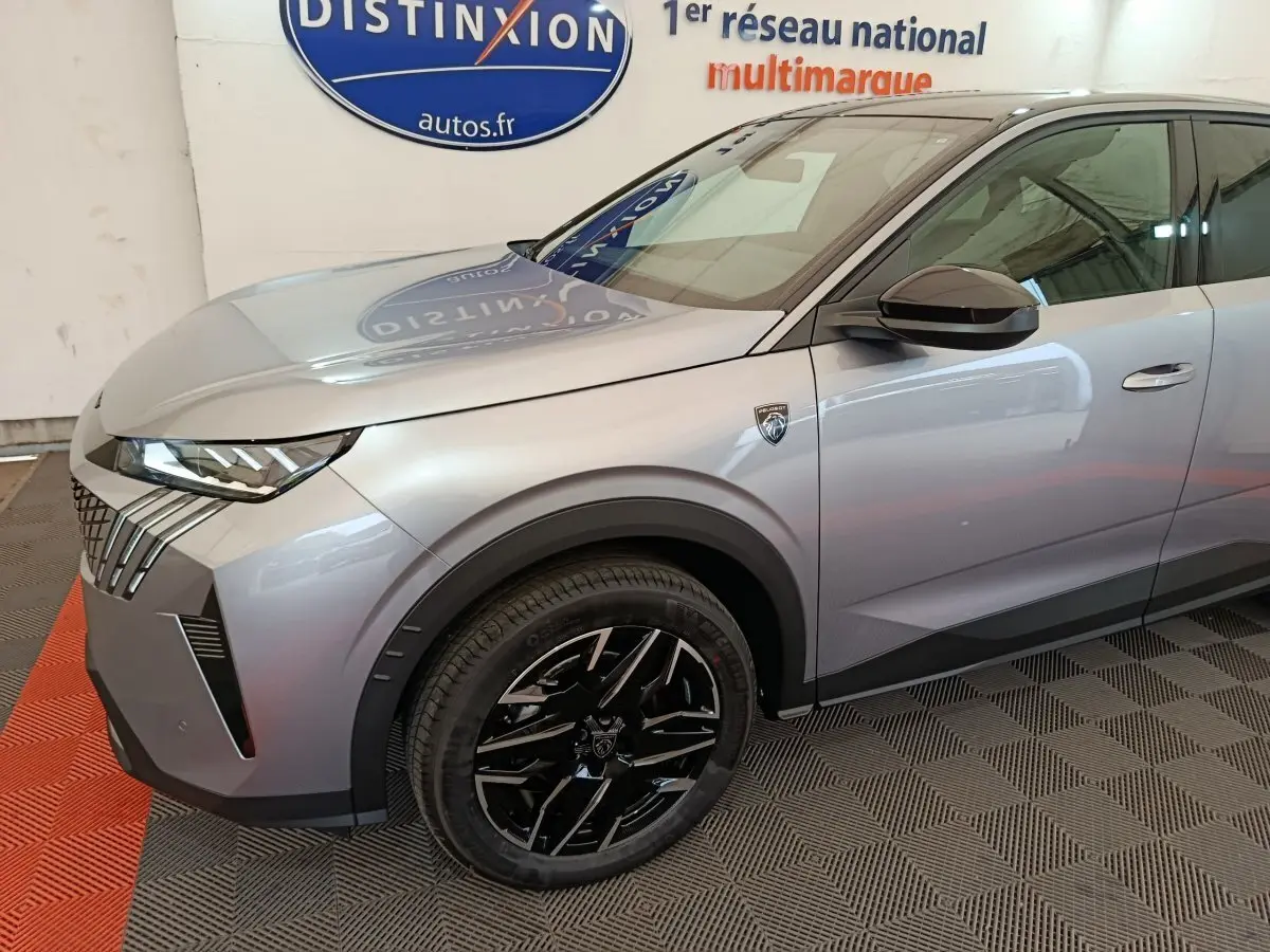 Vue 3/4 avant gauche d'un Peugeot 3008 gris clair avec jantes noires et logo distinctif sur l'aile avant.