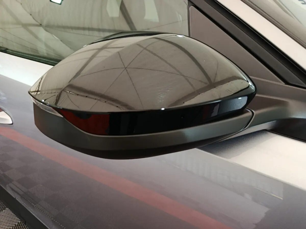 Gros plan sur le rétroviseur droit noir brillant du Peugeot 3008 gris clair hybride 2025, soulignant sa finition moderne.