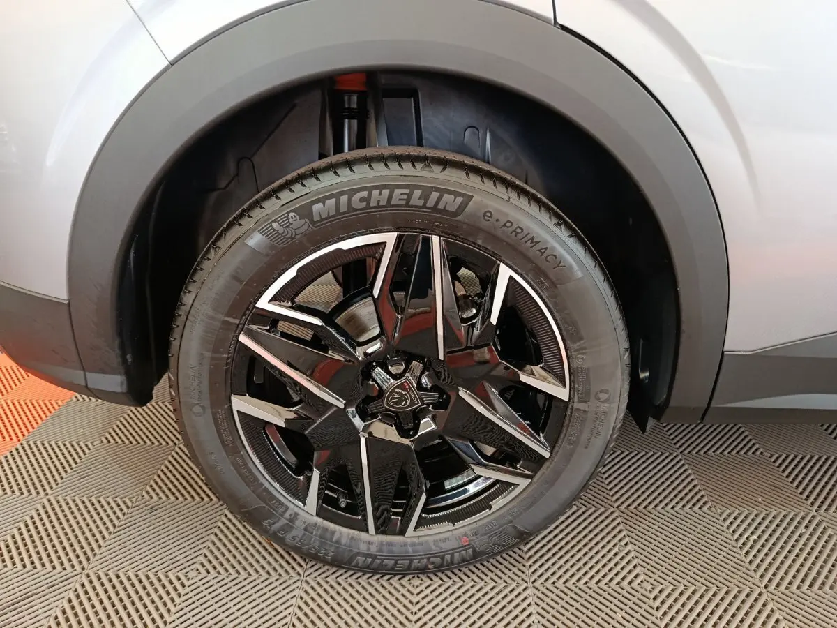 Gros plan sur la roue avant droite du Peugeot 3008 gris clair, jante alliage noir et argent avec logo lion central.