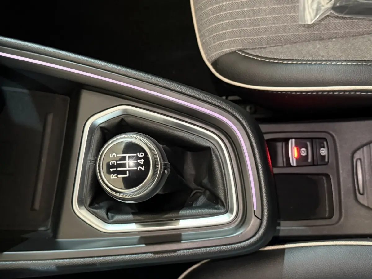 Gros plan sur le levier de vitesses manuel entouré d'un éclairage d'ambiance violet dans la Renault Clio Techno rouge.