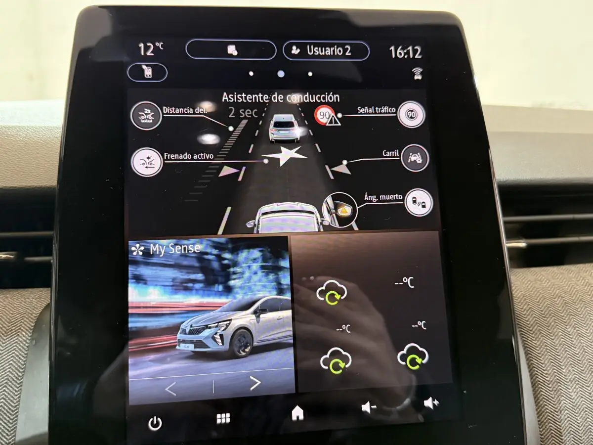 Écran tactile central affichant l'assistance à la conduite et une image de Renault Clio rouge en mouvement.