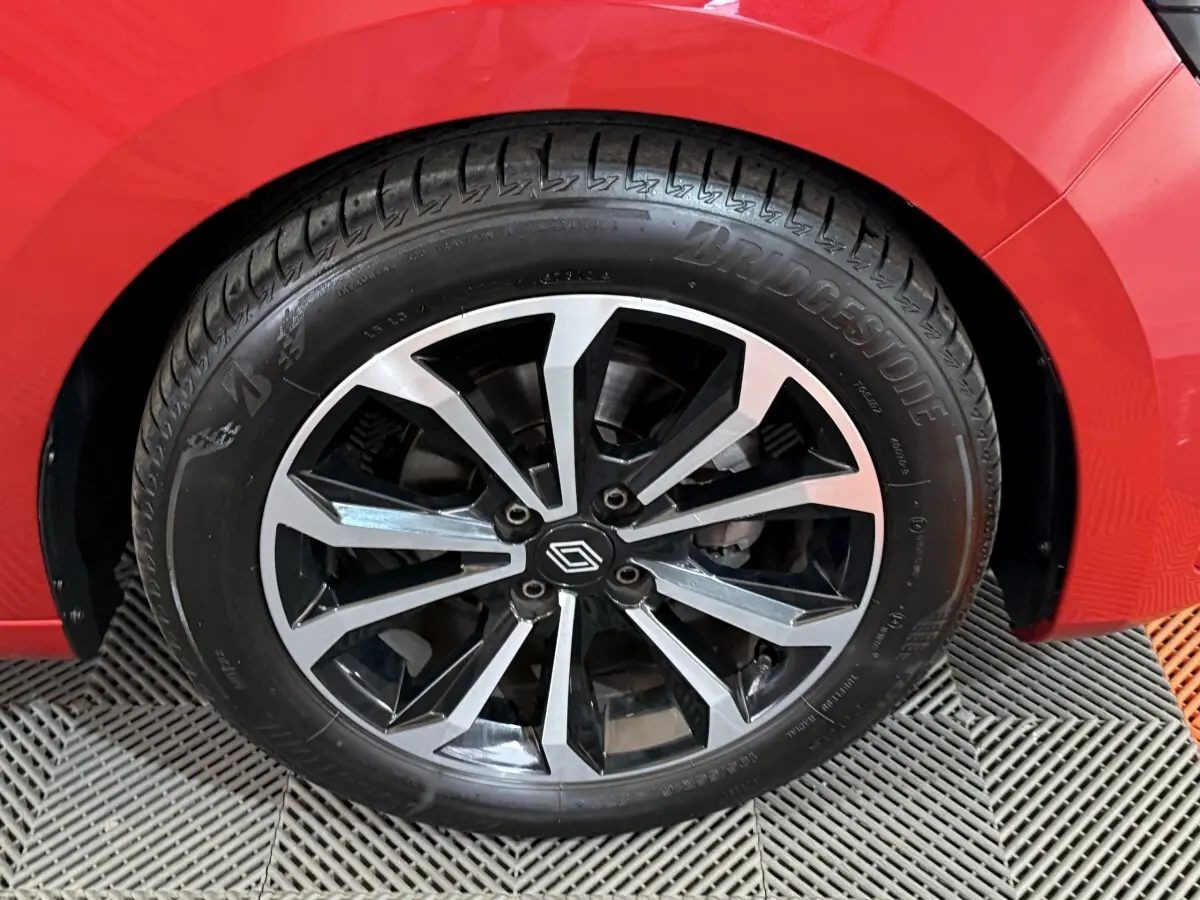 Gros plan sur la roue avant droite d'une Renault Clio Techno TCe 90 rouge, jante alliage noire et argent.