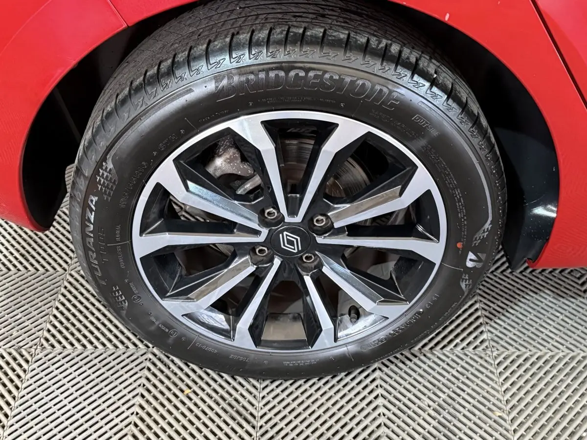 Gros plan sur la roue avant droite de la Renault Clio rouge 2024 avec jante alliage noire et argentée.