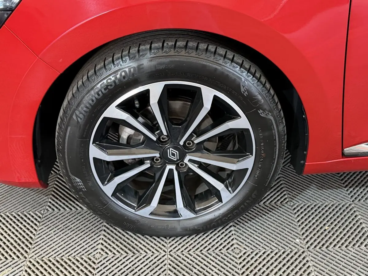 Gros plan sur la roue avant gauche de la Renault Clio Techno TCe 90 rouge, avec jante alliage noire et argentée.