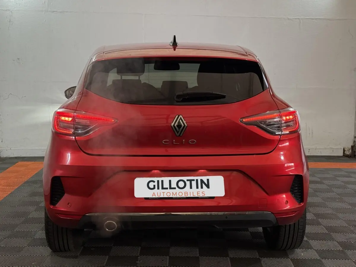 Vue arrière d'une Renault Clio Techno TCe 90 rouge 2024 avec feux LED allumés et fumée visible près de l'échappement.