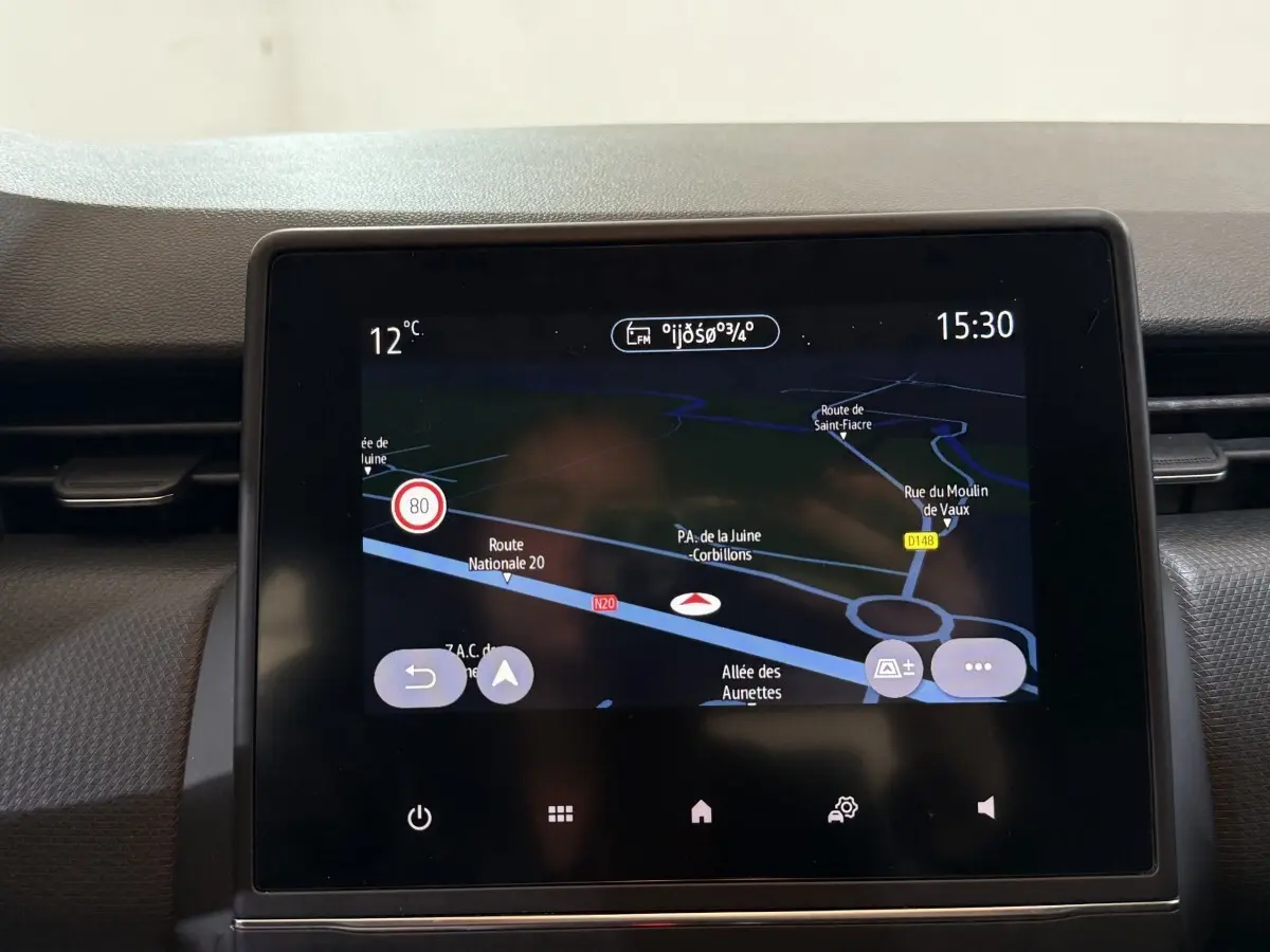 Écran tactile central du tableau de bord de la Renault Clio Business blanc, affichant la navigation GPS et la température extérieure.