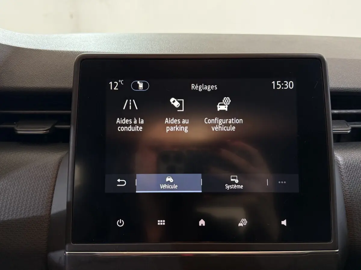 Écran tactile central de la Renault Clio Business blanc 2021 affichant les réglages d’aides à la conduite et parking.