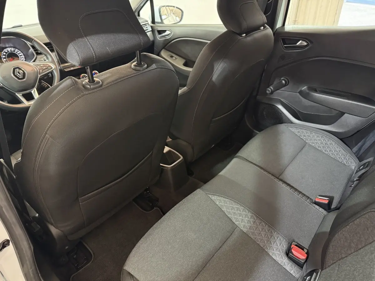 Vue arrière intérieure côté droit de la Renault Clio Business blanche, montrant les sièges arrière et dossier avant noir.