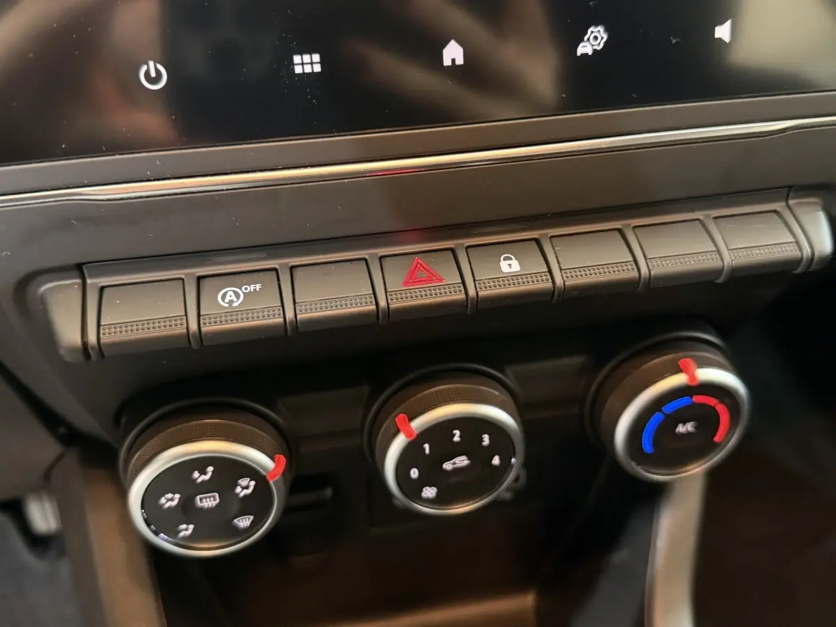 Gros plan sur les commandes de climatisation et boutons de fonction du tableau de bord de la Renault Clio Business blanche.