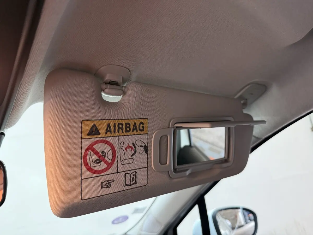 Détail du pare-soleil côté conducteur de la Renault Clio blanc 2021 avec miroir de courtoisie ouvert et avertissement airbag.