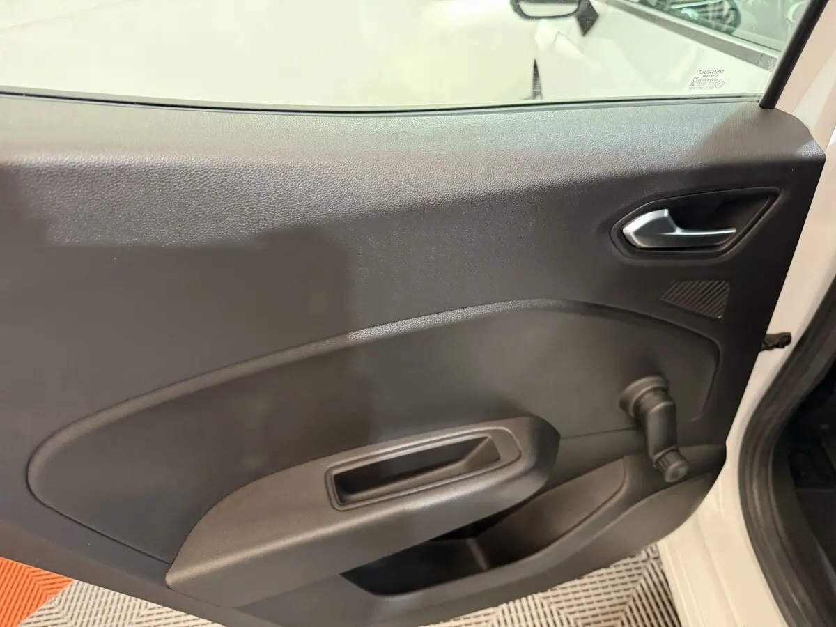 Vue intérieure côté gauche de la porte avant d'une Renault Clio blanche 2021 avec poignée manuelle de vitre.