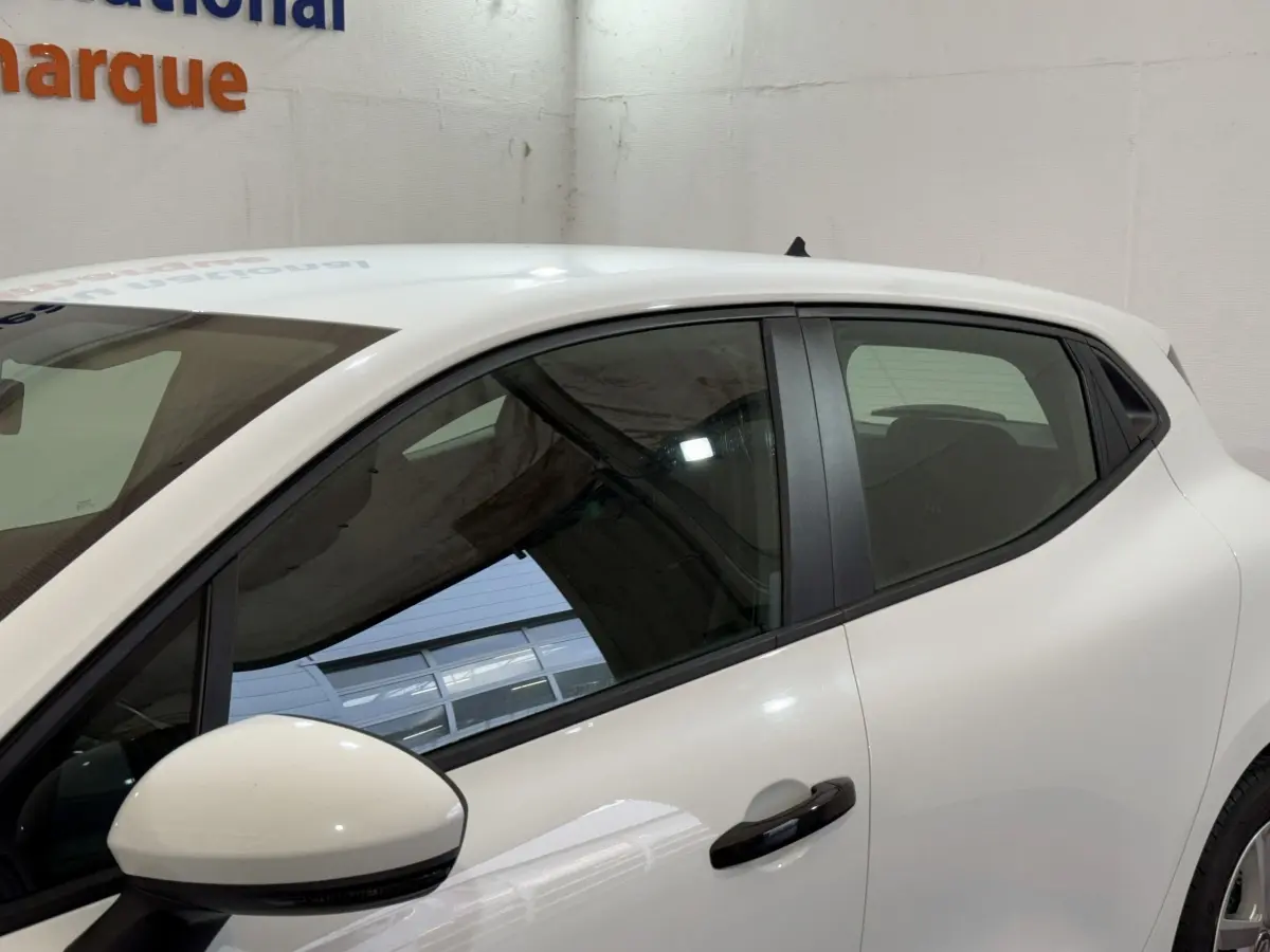 Vue latérale droite d'une Renault Clio Business blanche, avec rétroviseur et poignée de porte noirs visibles.