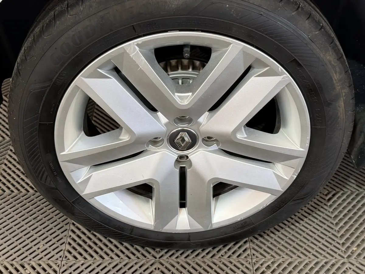 Pneu de secours noir monté dans le coffre d'une Renault Clio Business blanche, vue rapprochée du caoutchouc.