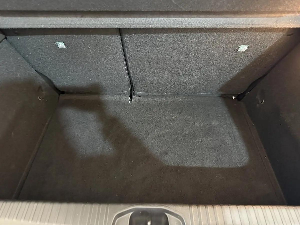 Vue plongeante sur le coffre noir de la Renault Clio Business blanche, montrant l’espace de rangement arrière.