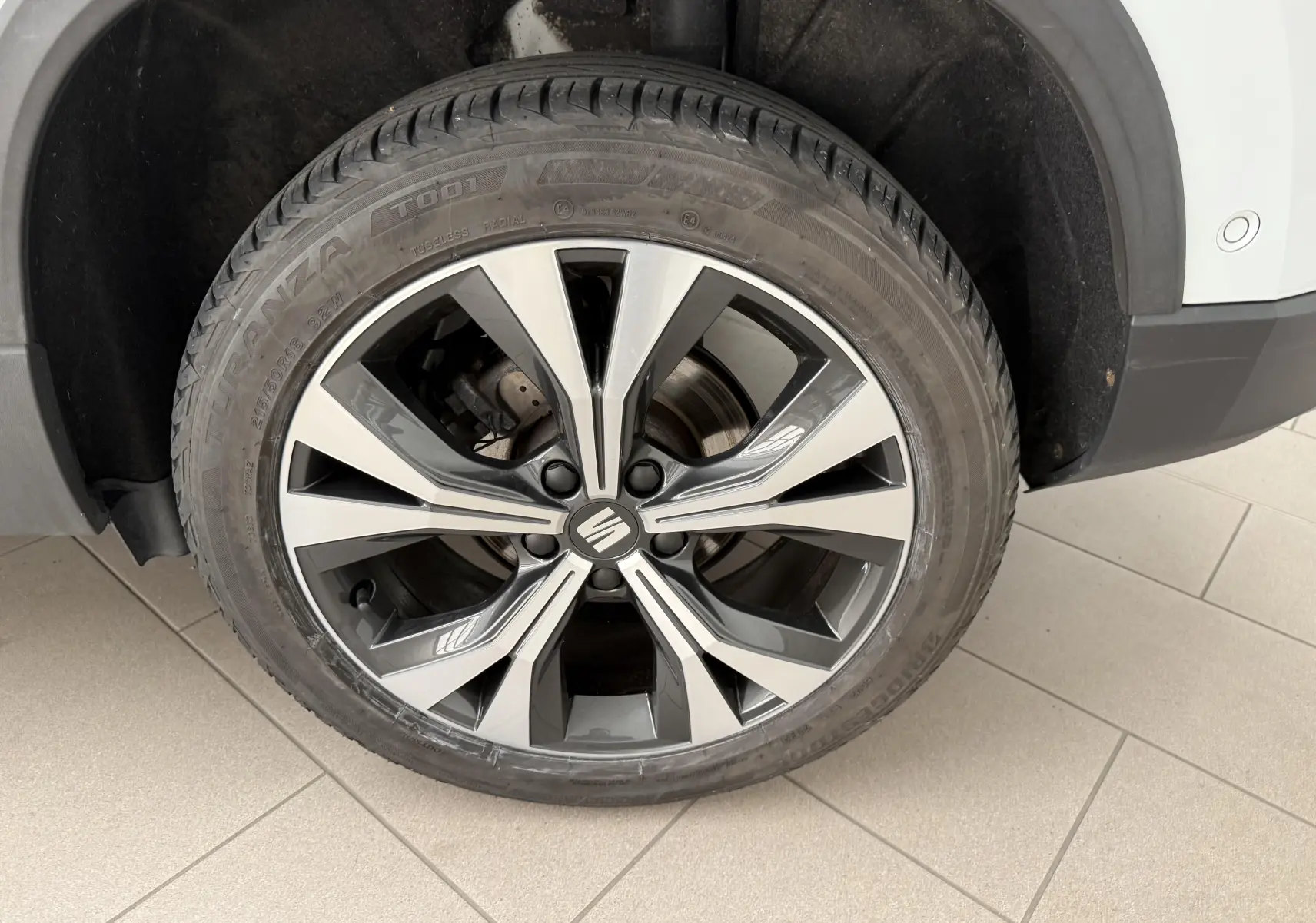 Gros plan sur la roue avant droite du SEAT Ateca blanc Nevada, avec jante alliage 18 pouces au design moderne.
