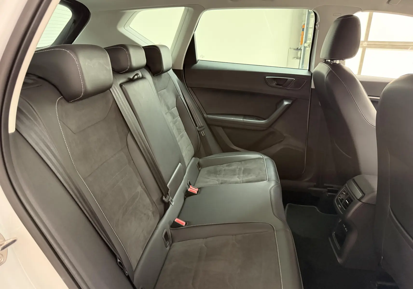 Vue intérieure arrière côté gauche du SEAT Ateca blanc Nevada 2023, sièges en cuir et alcantara noirs avec surpiqûres blanches.