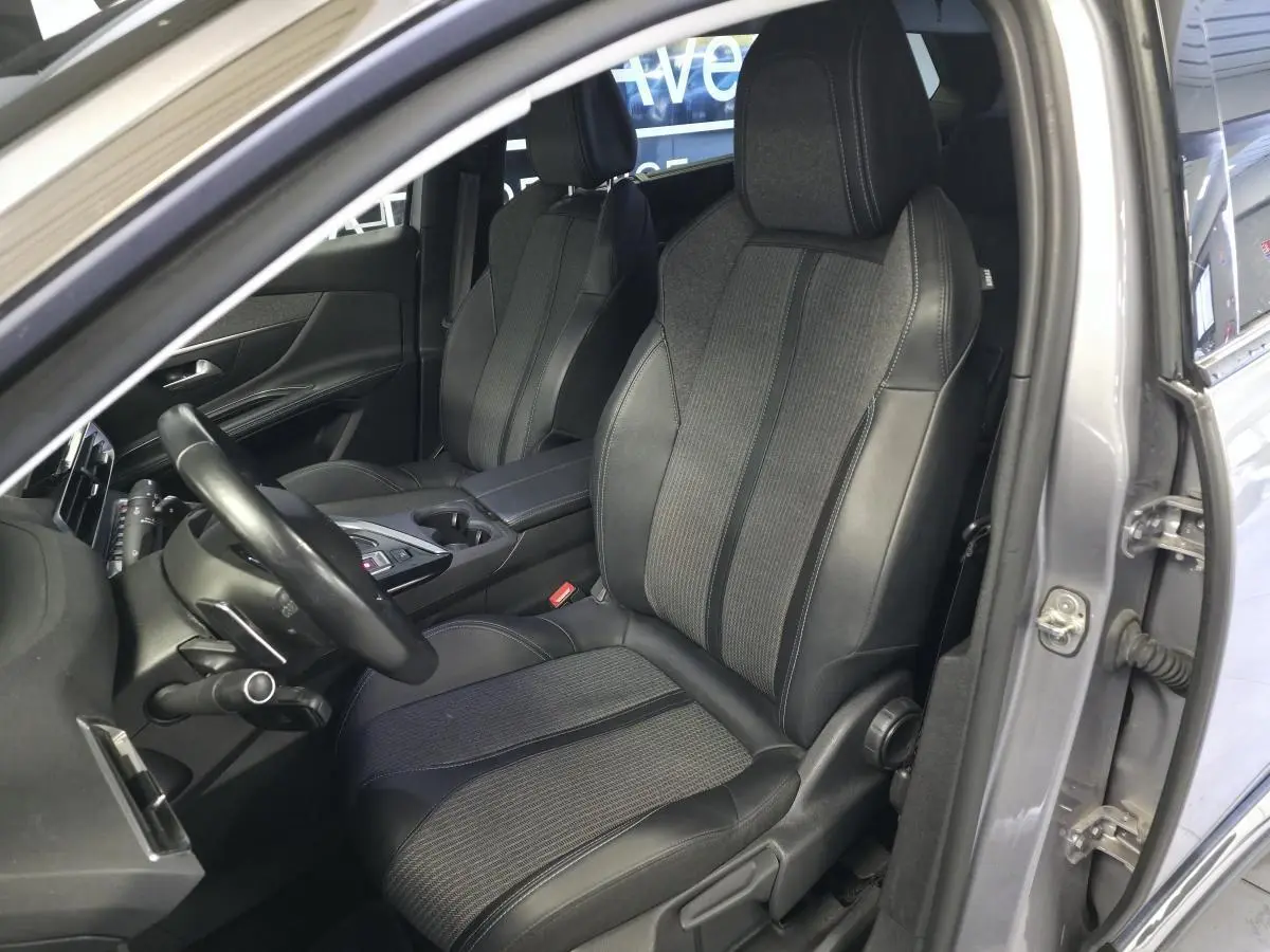 Vue intérieure côté conducteur du Peugeot 5008 gris 2022, mettant en valeur les sièges TEP & tissu et le volant cuir.