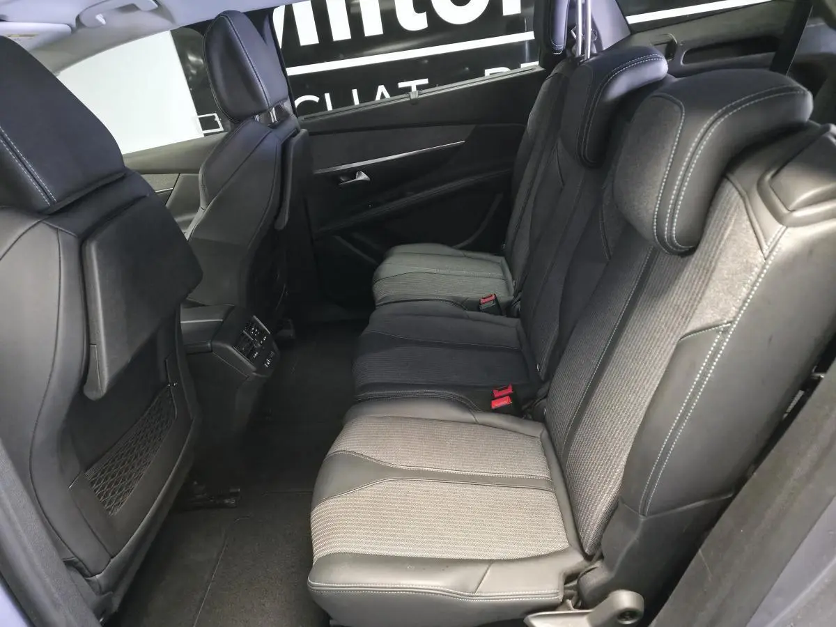 Vue latérale intérieure des sièges arrière gris et noirs du Peugeot 5008 2022 avec appuis-tête réglables et coutures contrastées.