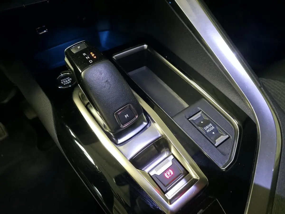 Gros plan sur la console centrale noire du Peugeot 5008 2022, avec levier de boîte auto et bouton Drive Mode.