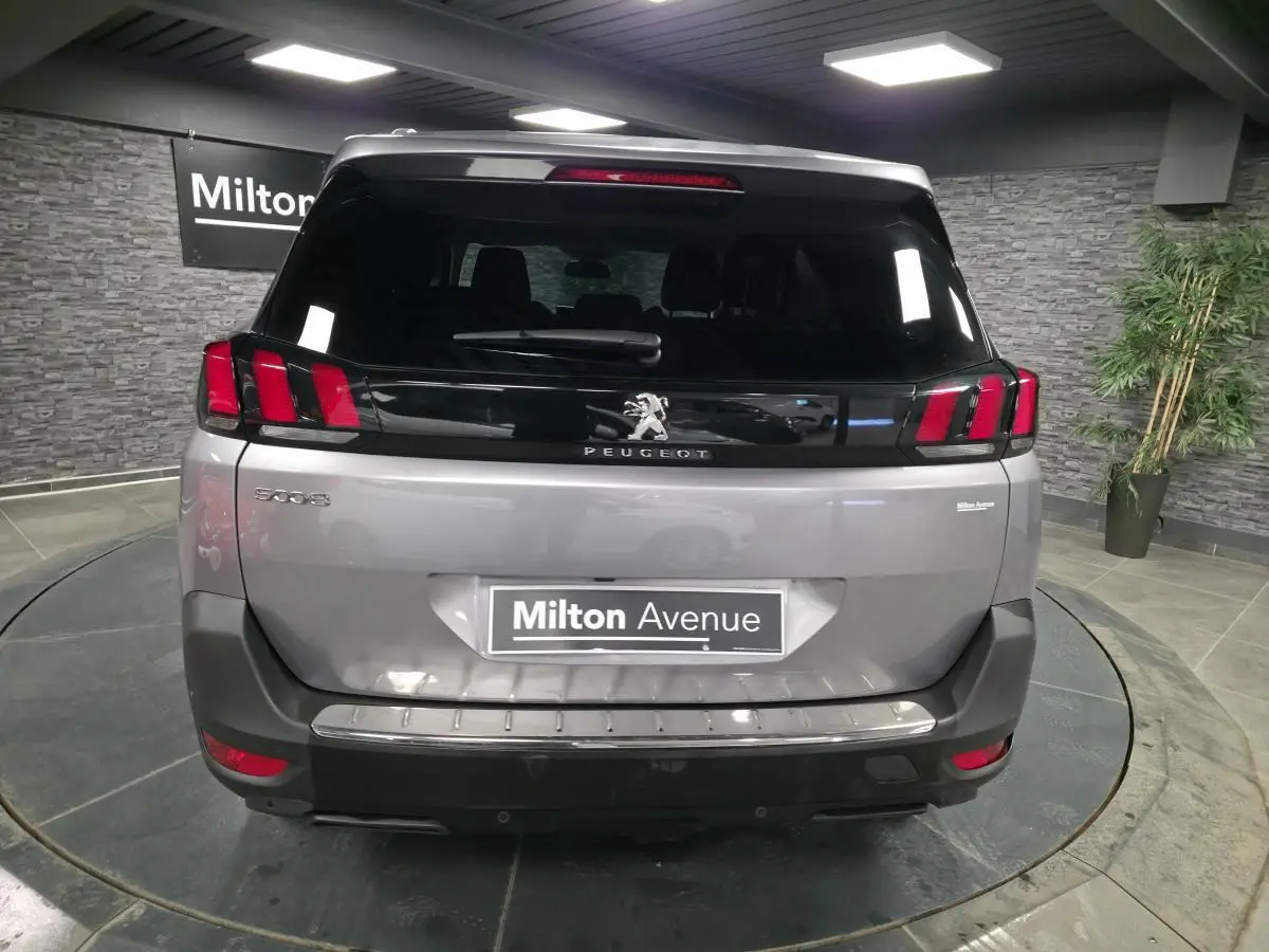 Vue arrière d'un Peugeot 5008 gris métallisé avec feux arrière à griffes rouges et logo lion central.