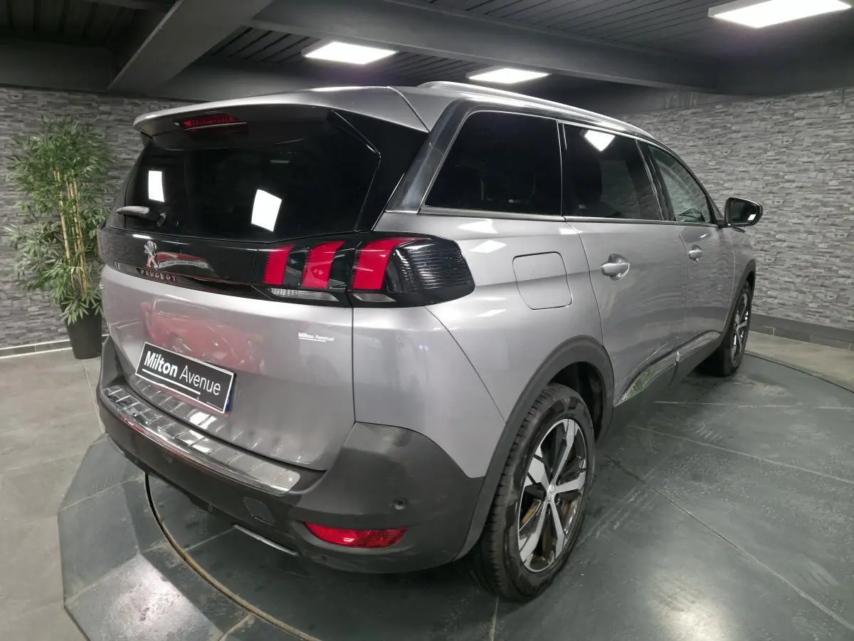 Vue 3/4 arrière droite du Peugeot 5008 gris métallisé avec vitres surteintées et jantes alliage bi-ton.