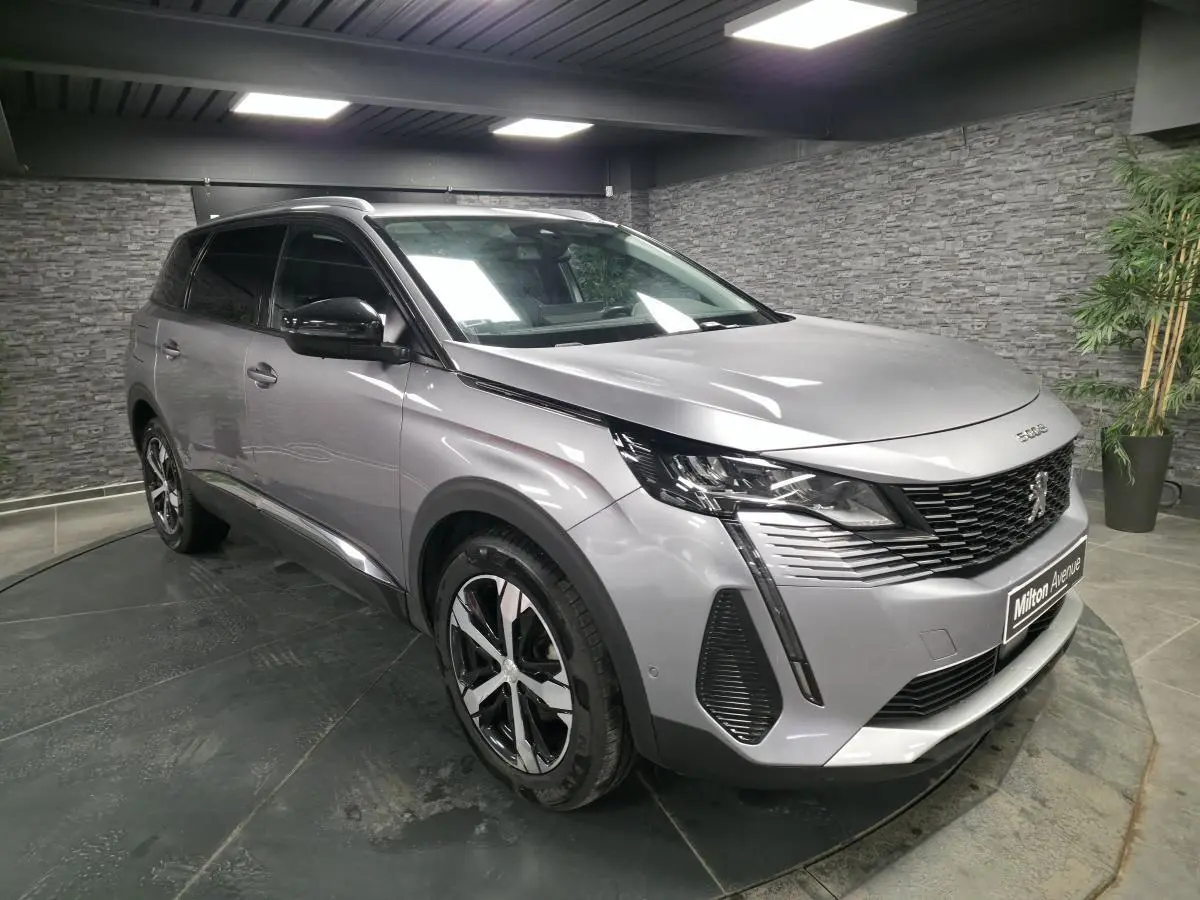 Peugeot 5008 gris métallisé vue 3/4 avant droit en intérieur avec jantes alliage bi-ton et calandre noire.