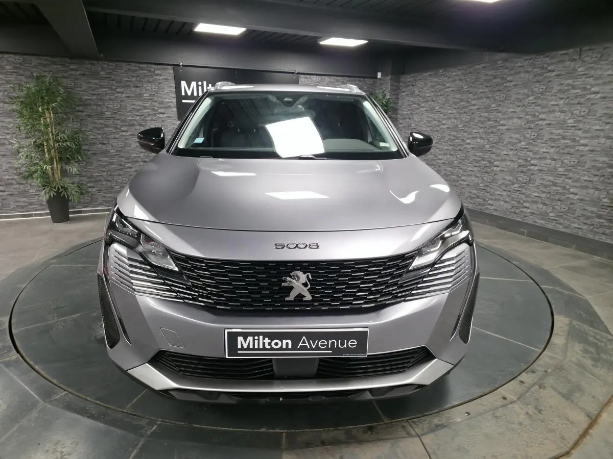 Peugeot 5008 gris métallisé vue de face, calandre à damier chromé et phares LED distinctifs.