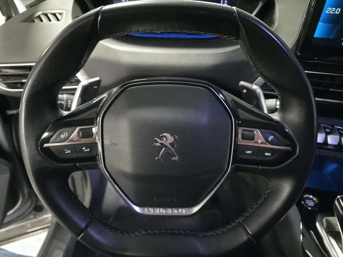 Volant compact en cuir noir du Peugeot 5008 2022, vue frontale centrée sur les commandes multifonctions et le logo lion.