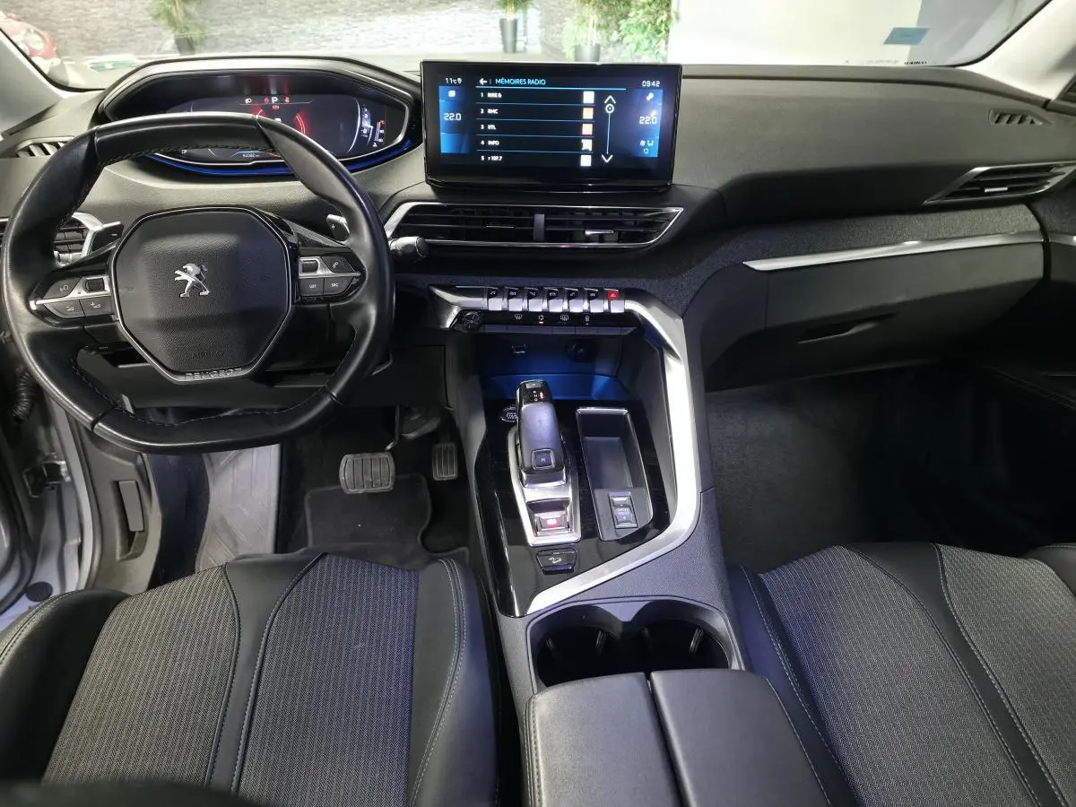 Vue intérieure avant du Peugeot 5008 gris, montrant le volant compact, l'écran tactile 10 pouces et la console centrale moderne.