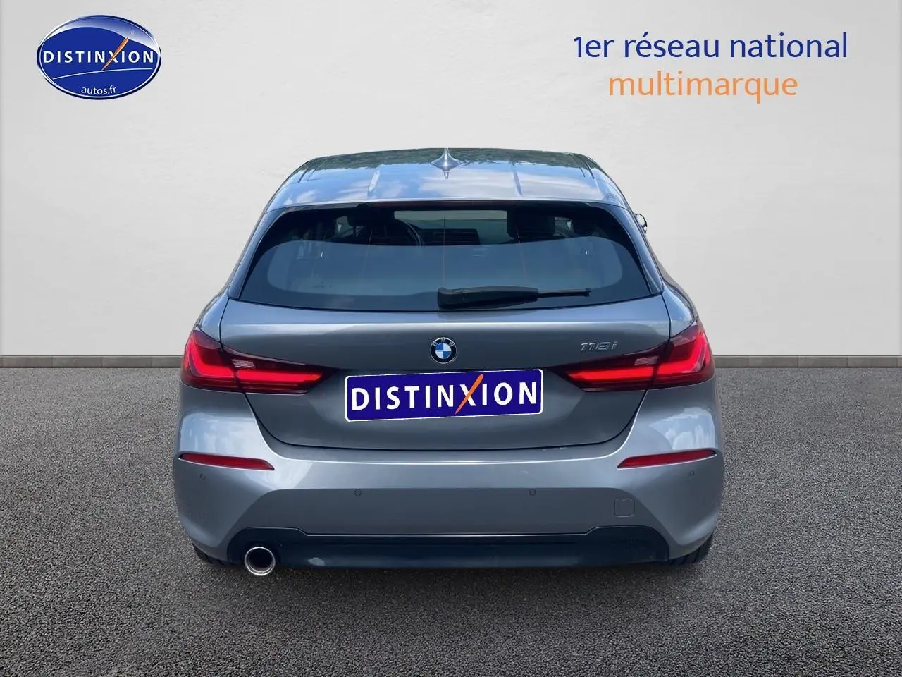 Vue arrière d'une BMW Série 1 gris foncé avec feux LED et sortie d'échappement visible côté gauche.